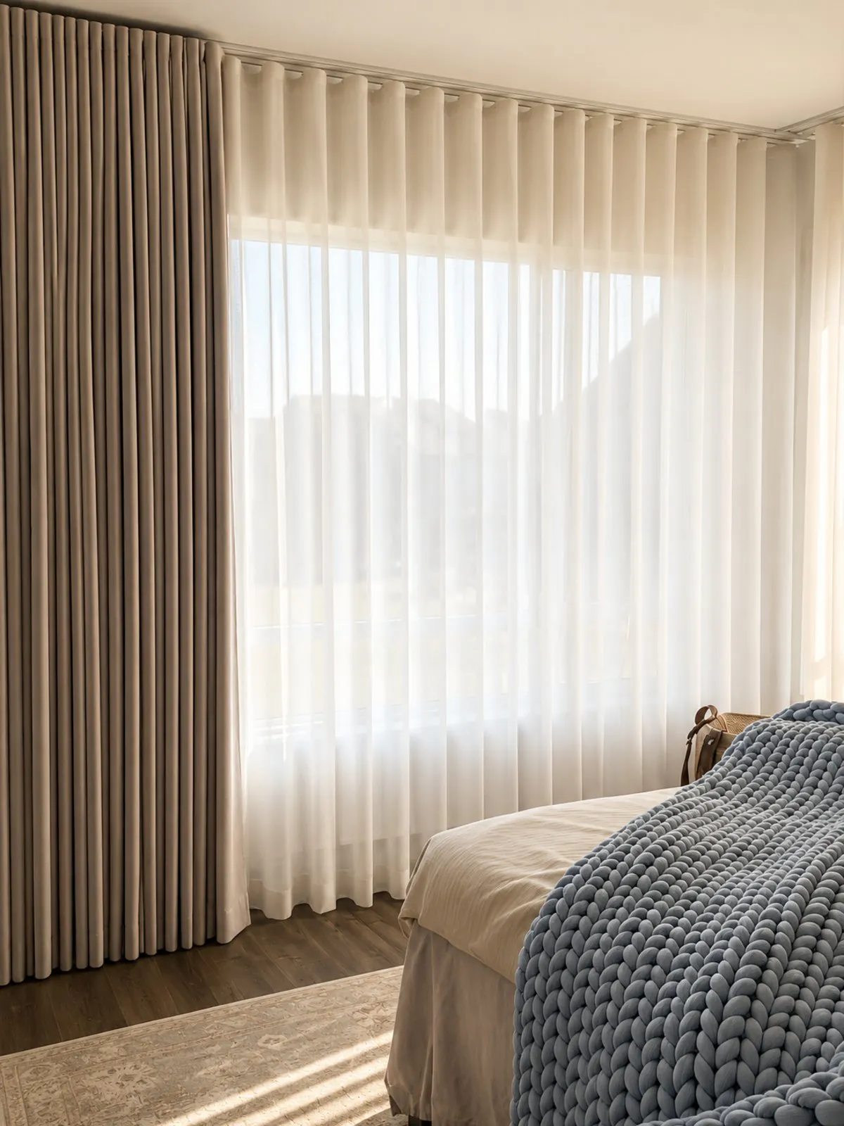 Sheer wave curtains layered with a blackout drape across a bedroom window