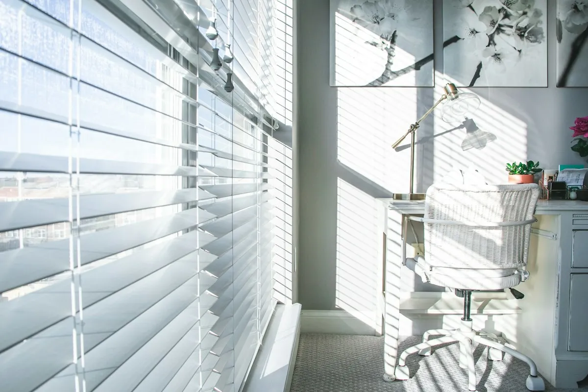 White faux wood blinds tilted open in a bright room
