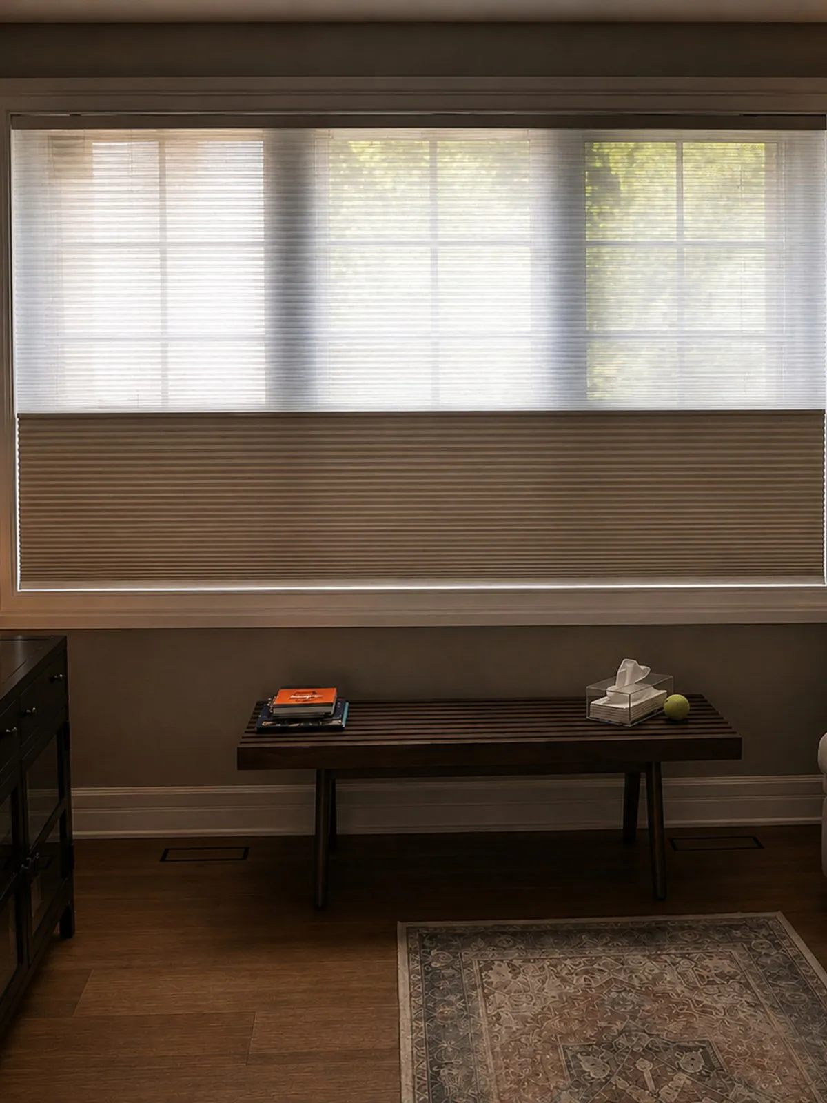 A top-down cellular shade on a wide window above a bench