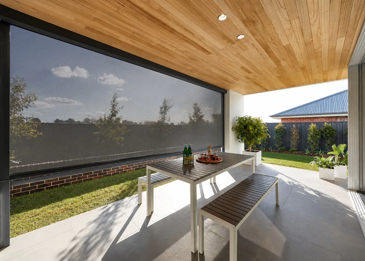 Looking out through an outdoor zip-track screen from a shaded patio